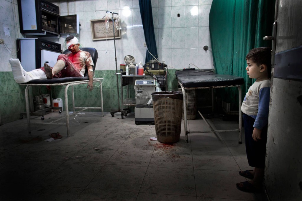 En liten pojke tittar på en skadad man i en av sjukhusets operationssalar. Foto: NICLAS HAMMARSTRÖM